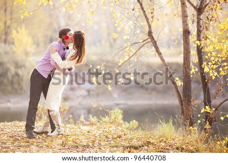 happy young couple kissing outdoor in the autumn park