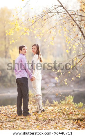 happy young couple walking away and turning around outdoor in the autumn park