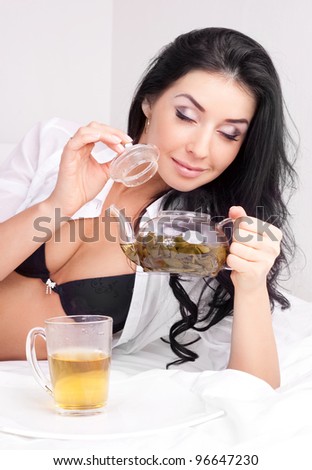 sexy brunette woman drinking green tea in bed at home