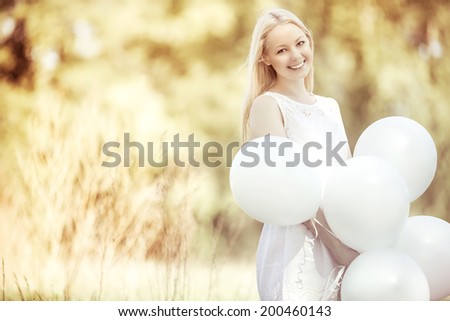 happy young woman with white balloons in the summer park