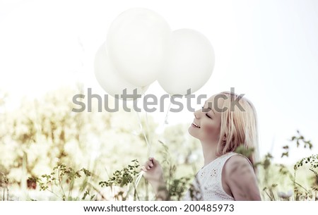 happy young woman with white balloons in the summer park
