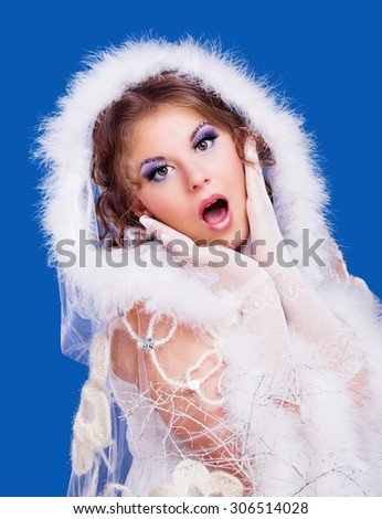 surprised woman wearing a fur-coat, isolated against blue background, winter topic