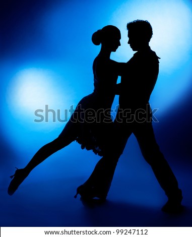 A silhouette of a couple dancing against blue studio background