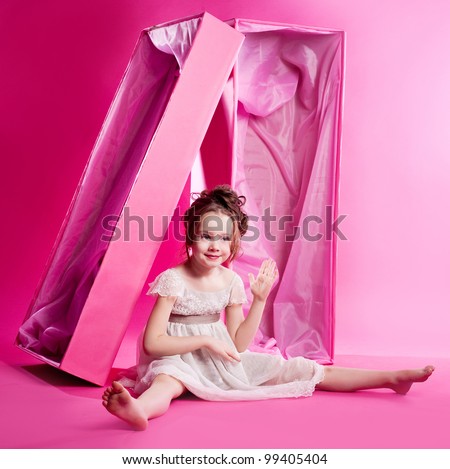 cute six year old girl photographed as an alive doll in the pink box,  against pink studio background