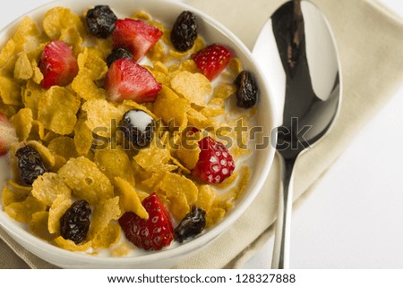 Bowl with corn flakes, strawberry, dried grape and milk for breakfast