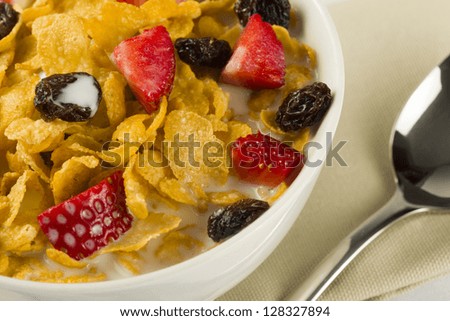 Bowl with corn flakes, strawberry, dried grape and milk for breakfast