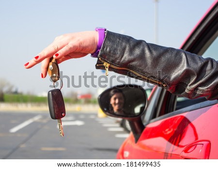 girl holding car key out the car window