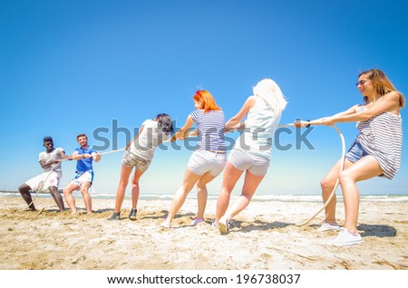 Group of friend playing at tug of war - men against women