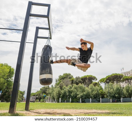 training at the crossfit park, man executes flying kick on the bag
