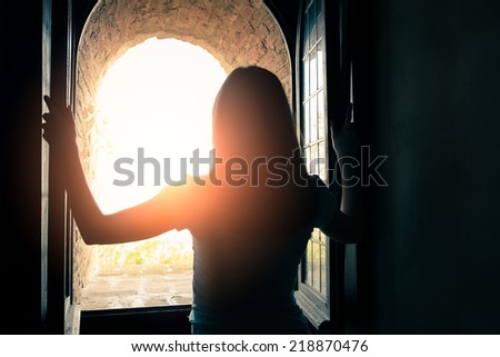 Silhouette of beautiful woman opening window
