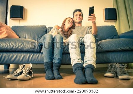 Happy couple watching television on the couch - family,recreation,leisure,togetherness concept