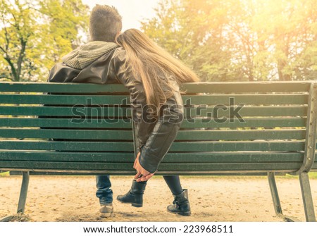 Couple on a bench - Two lovers sitting on a bench in a park and holding themselves by hands - Concepts of autumn,love,togethe rness,relationship