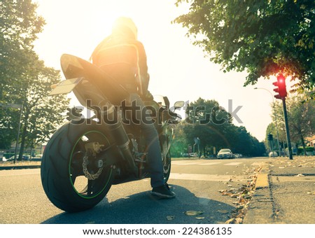 Motorcyclist on the road - Racing motorbike stops at traffic lights at sunset