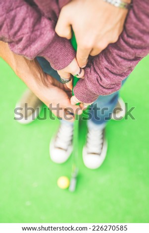 couple playing mini golf. Man helping his girlfriend to hold the club. concept of union and love