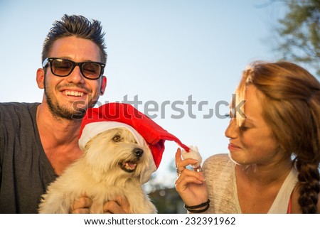 Portrait of young happy couple and dog with christmas hat
