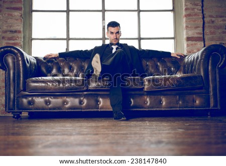 rich man sitting on a couch in a luxury apartment.