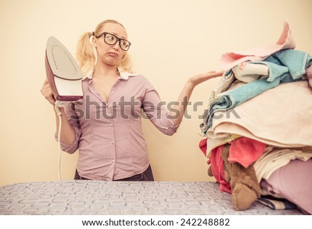 Housewife with iron looking unhappy at a pile of clothes
