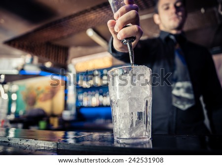 barman at work, pouring spirit into a glass. concept about professions and drinks