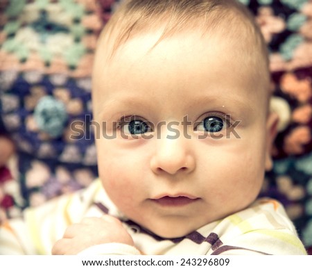 Portrait of playful baby with blue eyes - Candid image of young boy playing at home