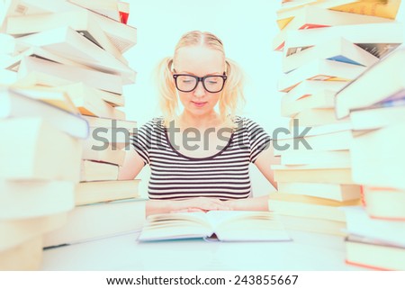 Young student reading a book among pile of books - Pretty woman studying in a library