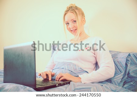 Young woman in bed with computer - Woman looking news at computer laptop