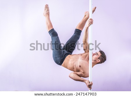 young man performing pole dancing moves on the pole