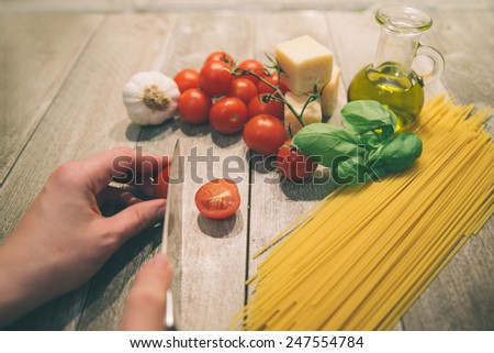 Housewife preparing pasta with tomato sauce -Pasta,tomatoes and spices on a wood table - Spaghetti and ingredients for a a great italian tomato sauce