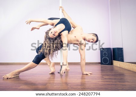 Couple dancing at pole in a fitness studio - Ballet dancers working out