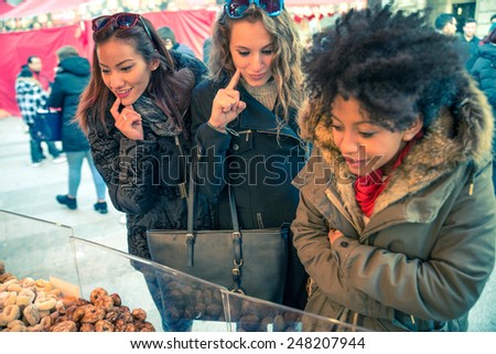 Women looking at food in a outdoors market - Three friends buying yummy sweets at market stand