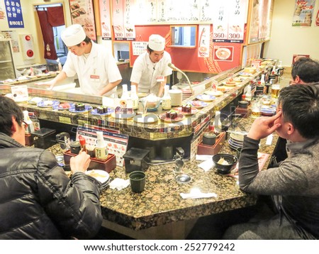 TOKYO,JAPAN - FEBRUARY 11,2015: people eating in a Sushi restaurant in Tokyo.Sushi is a traditional japanese specialty known all over the world.