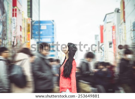 japanese woman standing in the crowd in tokyo city center. she looks amazed at the buildings