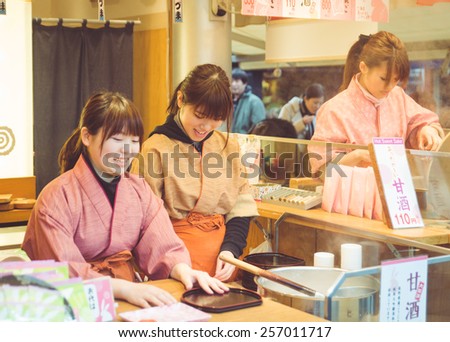 Tokyo, Asakusa. February 8, 2015. Japanese girls working in a street food store wearing kimono. kimono is the traditional Japanese clothes that means \