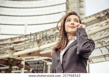 Business woman talking at phone - Asian woman with elegant dress and skyscraper in the background  - Business,technology,multiracial concepts