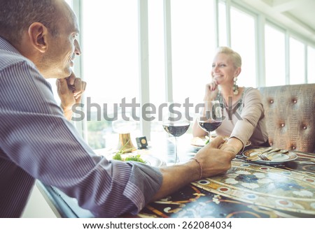 middle age couple having lunch in a fancy restaurant with view on the ocean. concept about food,industry,people,vacations,and love