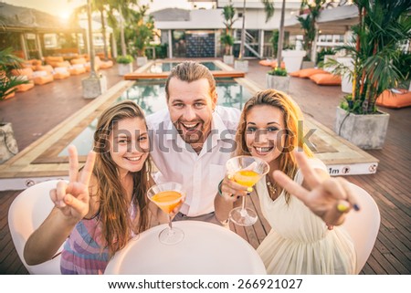 Friends at party drinking cocktails and having fun - Three tourists drinking aperitif in a tropical luxurious restaurant