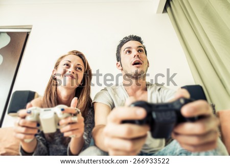 couple playing video games on the couch. concept about home entertainment, video games, people and couple