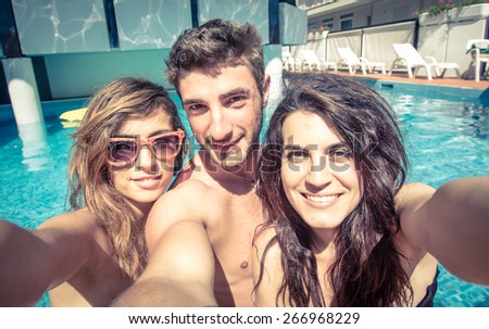 three friends taking selfie in the swimming pool. concept about friendship, people,technology,selfie, and fun