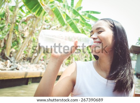 happy smiling asian woman drinking water from the bottle. concept about healthy lifestyle and people