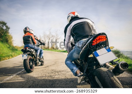 Two motorbikes driving in the nature - Friends driving racing motorcycles with their girlfriends - Three friends riding sport bikes on a week-end tour