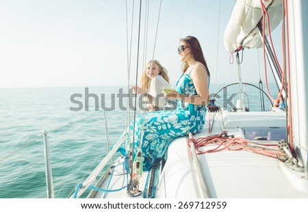 two young women sitting on he side of the boat and enjoying the good weather. concept about boat and party tour, happiness, ocean and people