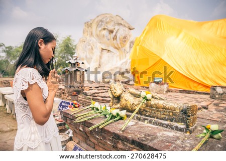 Asian woman praying at Buddha temple in Ayutthaya, Thailand - Young beautiful thailand girl with linked hand in sign of respect to religious statue