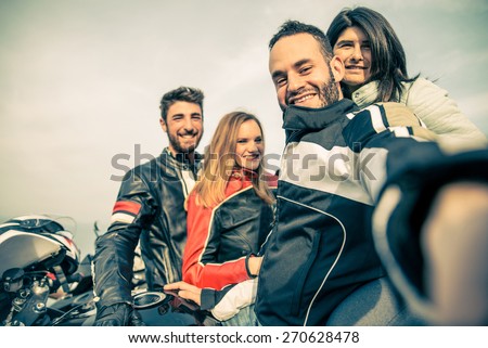 Bikers taking selfie with camera - Four smiling friends driving racing motorcycles with their girlfriends  - Two happy couples stop in a panoramic view point and photographing themselves