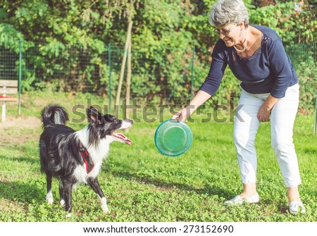 playing with the dog. middle age woman playing with her border collie dog in the park. throwing frisbee