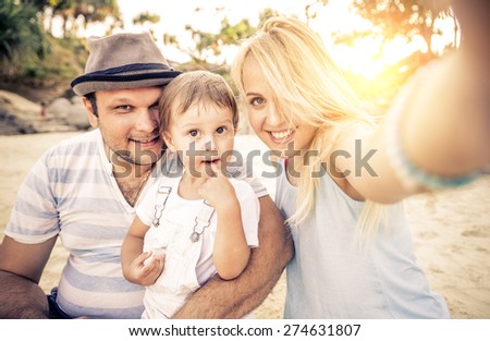 Mom and dad playing with their handsome son - Family and baby outdoors - Young beautiful mother taking a self portrait with her family