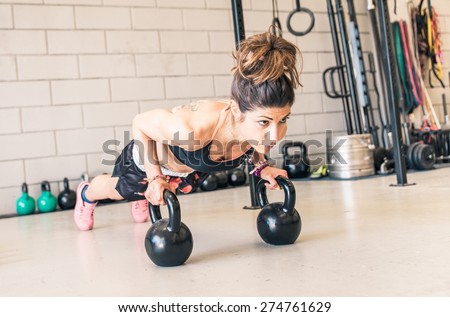 woman making push ups on the kettle bells in a gym. concept about fitness, sport and people