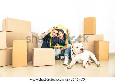 Happy couple with dog moving to a new home - Cheerful family starting a new life - Multi ethnic couple of lovers buy new apartment