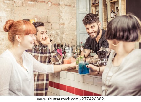 group of friends in a bar having fun with the bartender. concept about job,friendship,service,profession,and people