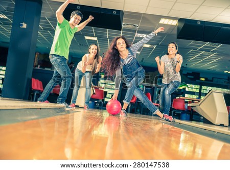 Group of friends at bowling - Young people having fun at bowling,one girl is throwing ball and friends supports her