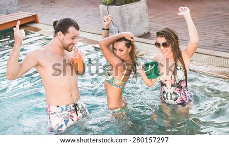 party in the swimming pool. three friends drinking and dancing on the roof top pool
