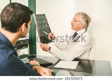 Doctor with x-ray plate talking with his patient in a clinic studio - Young man with health problem in hospital receive prognosis from radiologist